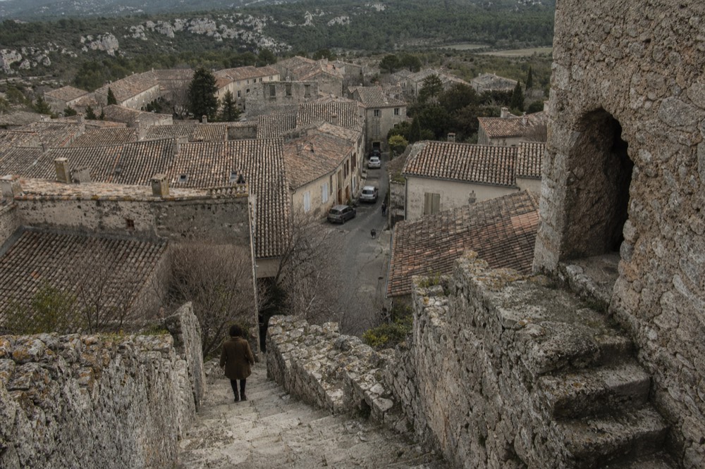 A ruined stone castle keep standing above a Provençal village and surrounding countryside, no text, no logos, no people