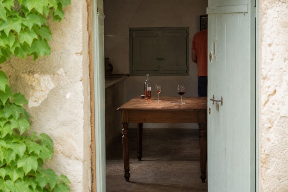 A tasting room table with glasses of red and rosé wine beside an open bottle, no text, no logos, no people