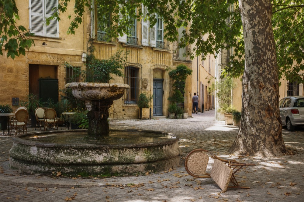 Courtyard of a Provençal townhouse in Aix with plane trees and a fountain, no text, no logos, no people