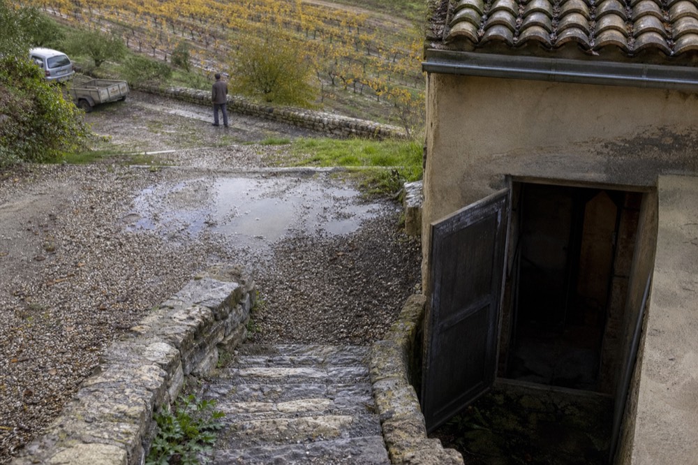 Gravel courtyard and stone steps leading to a cellar door in a Provençal wine estate, no text, no logos, no people