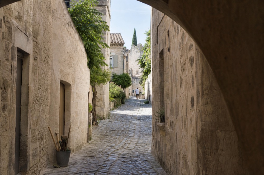 Narrow limestone street in Les Baux-de-Provence with old stone houses, no text, no logos, no people.