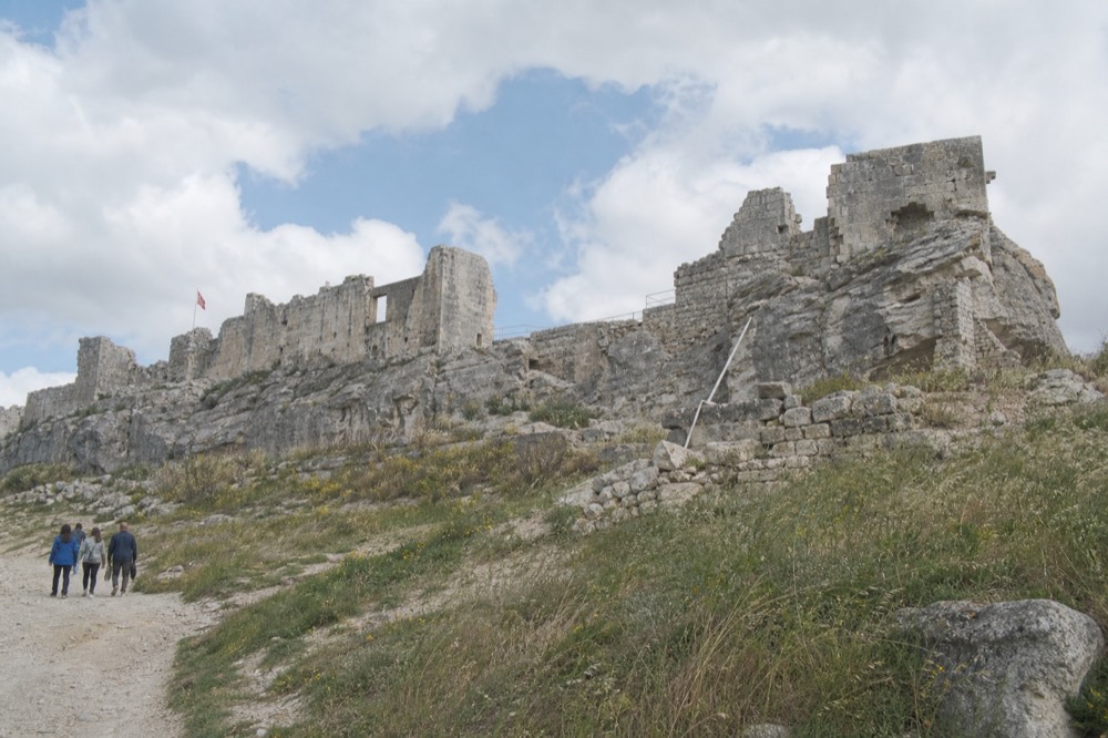 Ruined stone walls of the Château des Baux on a rocky ridge overlooking plains, no text, no logos, no people.