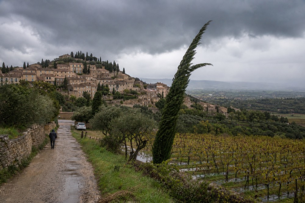 Dark storm clouds over a Provençal hillside village and vineyards, no text, no logos, no people