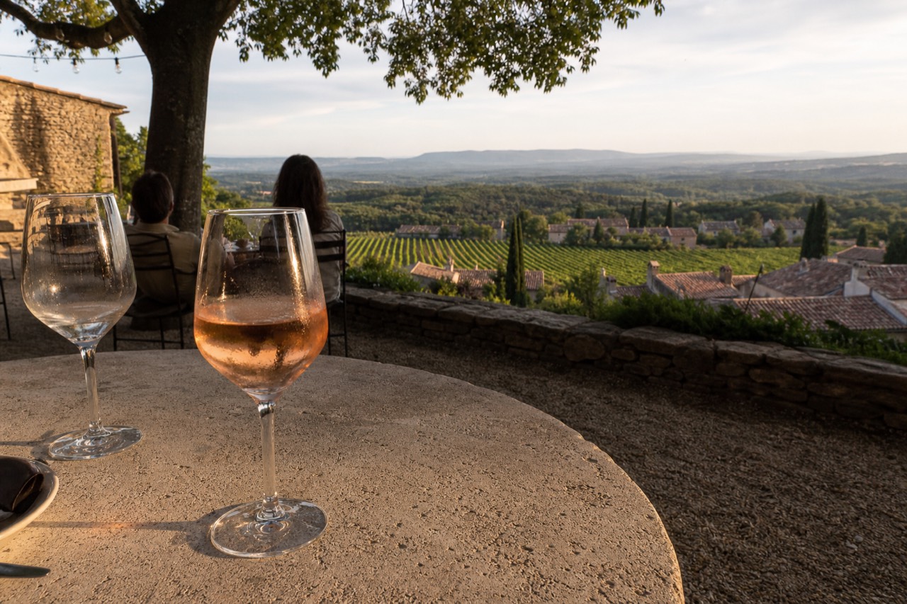 A glass of pale pink Provence rosé on a sunny terrace overlooking vineyards, no text, no logos, no people