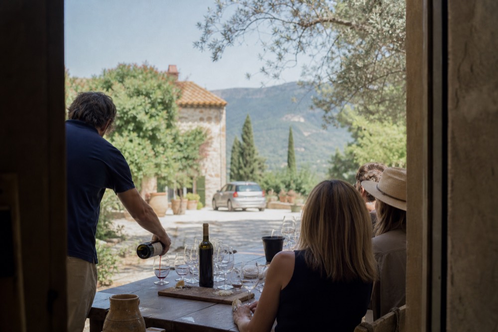 A guide pouring wine for a small group at an estate tasting table, no text, no logos, no people