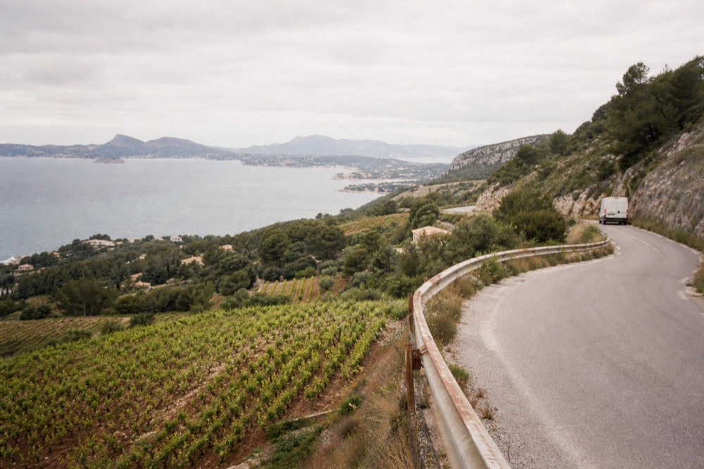 A winding coastal road with vineyards on the hillsides, no text, no logos, no people