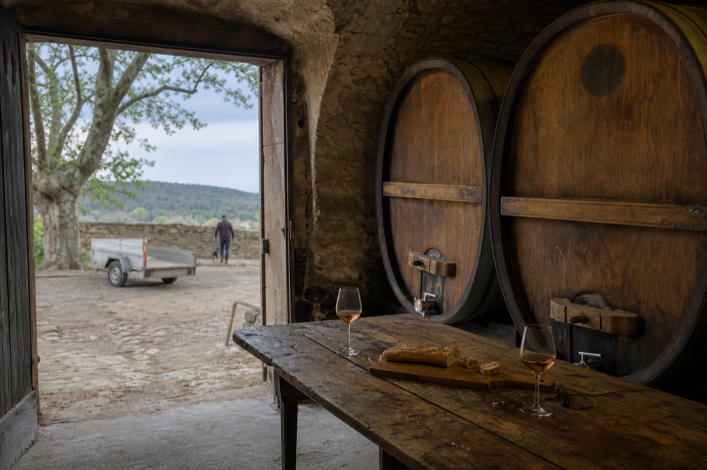 A small group tasting wine at a wooden table in a Châteauneuf-du-Pape cellar, no text, no logos, no people