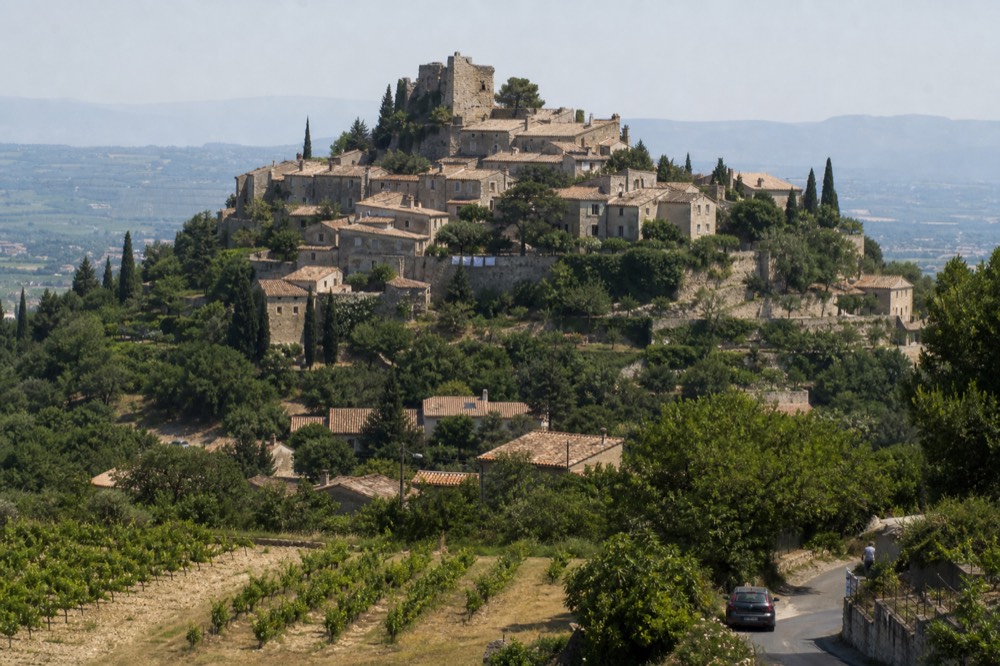 Luberon hilltop village with stone houses and distant vineyards, no text, no logos, no people