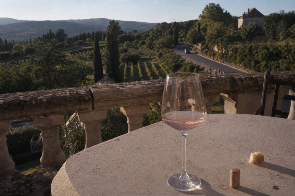 Glass of Luberon rosé on a terrace overlooking vineyards, no text, no logos, no people