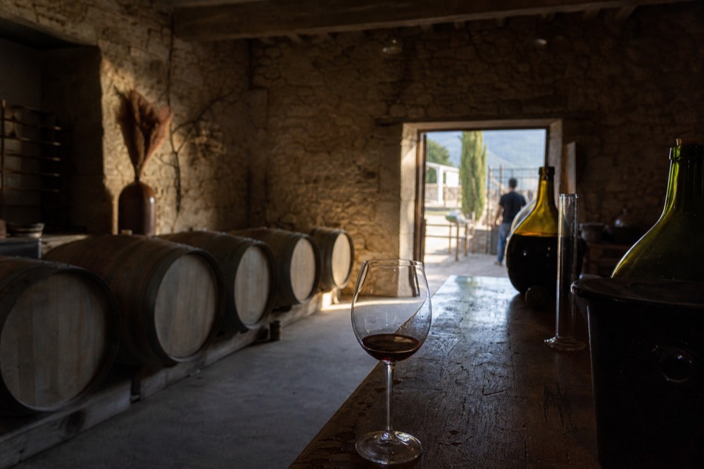 A tasting room with barrels and a glass of red wine, no text, no logos, no people