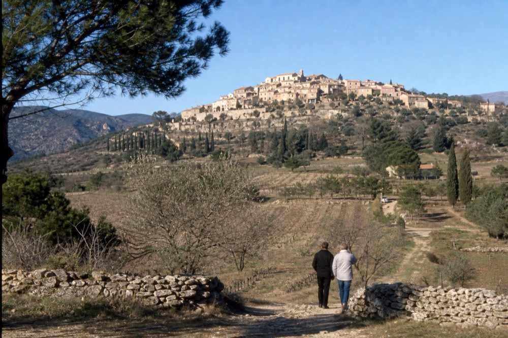A hilltop village surrounded by vineyards under a clear blue sky, no text, no logos, no people