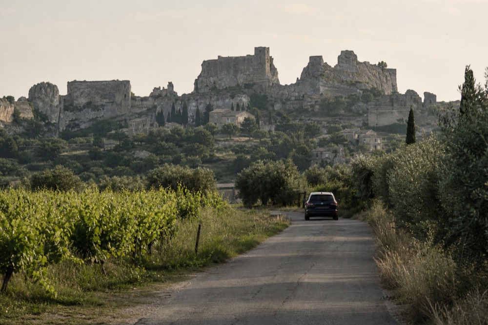 A narrow road winding through vineyards toward a medieval village, no text, no logos, no people